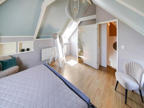 a attic bedroom with a bed and a chair at Beautiful Apartment in Callantsoog near Beach in Callantsoog