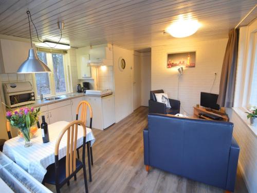 a kitchen and a living room with a table at Completely detached bungalow in a nature-filled park by a large fen in Stramproy