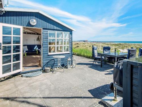 a blue house with a patio and a table at 4 person holiday home in Grenaa in Grenå