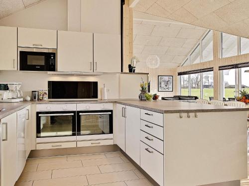 a white kitchen with white cabinets and appliances at 5 star holiday home in Bogense in Bogense