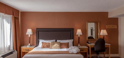 a bedroom with a bed and a desk and a mirror at Coast Hillcrest Hotel in Revelstoke