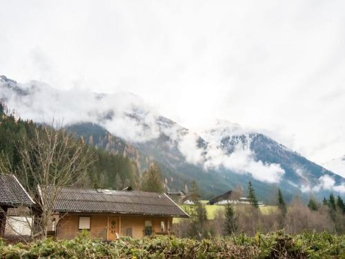 a house in front of a mountain with clouds at Lovely Apartment with Sauna, Ski Storage, Pool, Terrace in Wald im Pinzgau