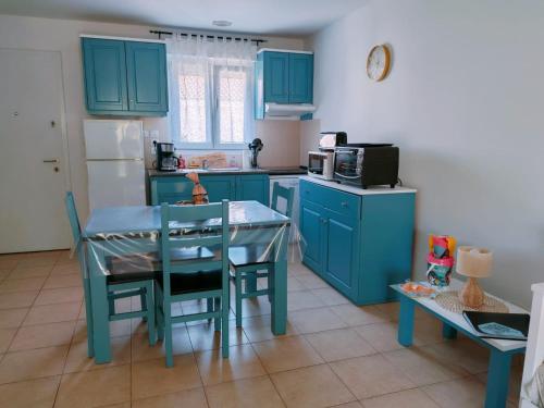 eine Küche mit blauen Schränken und einem Tisch mit Stühlen in der Unterkunft Mini Villa 200 m de la plage in Cervione