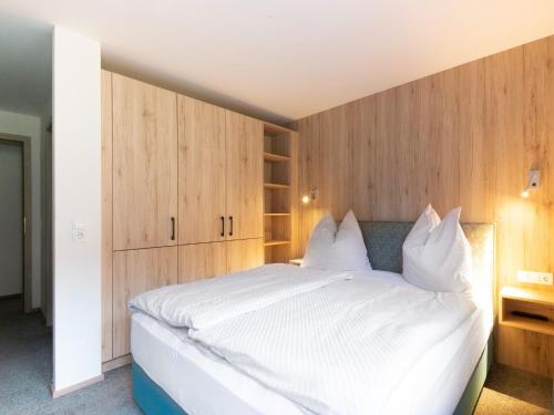 a bedroom with a large white bed with wooden cabinets at Lovely Apartment with Sauna, Ski Storage, Pool, Terrace in Wald im Pinzgau