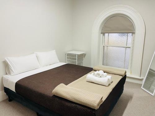 a bedroom with a bed with a window and two towels at Seafield Tower Glenelg Apartment in Glenelg