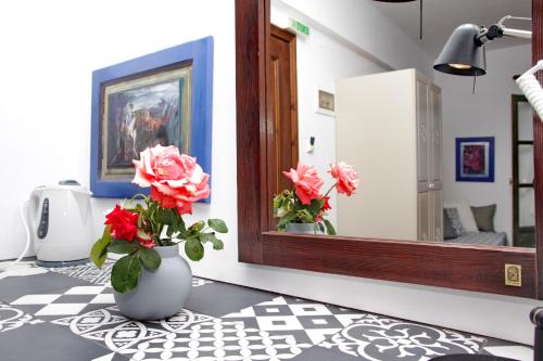 a vase with flowers in a room with a mirror at Aperanto Galazio in Skopelos Town
