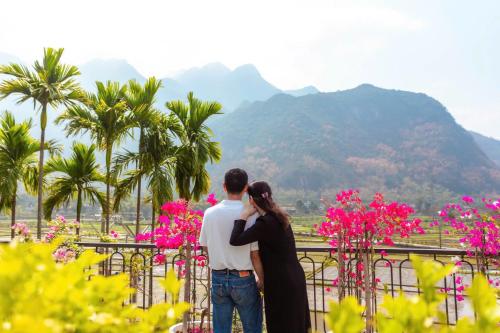 a man and woman standing next to a fence with pink flowers at Mai Chau La Luna in Mai Chau