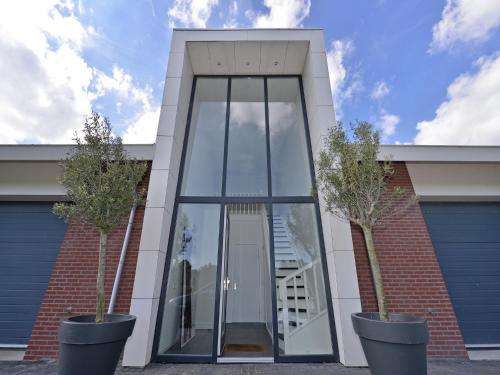a building with a large glass door and two trees at Waterfront penthouse with roof terrace and private jetty in Kamperland