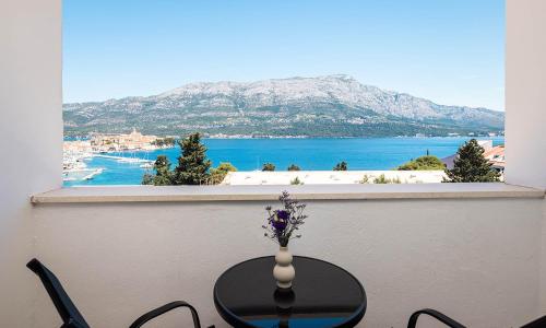 a table with a vase of flowers on a balcony at Marko Polo Maradiso Hotel by Aminess in Korčula