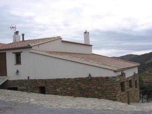 a white house with a stone wall and a building at Beautiful holiday home in Laroya with shared pool in Laroya