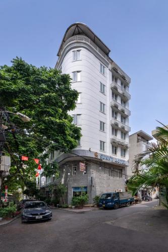 a white building with cars parked in front of it at Sunny Hotel in Hanoi