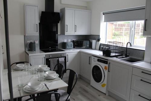 a kitchen with white cabinets and a table with a washing machine at House - Sleeps 4 - Parking - Garden - City Centre in Leeds