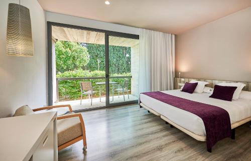 a hotel room with a bed and a large window at URH - Hotel Molí del Mig in Torroella de Montgrí