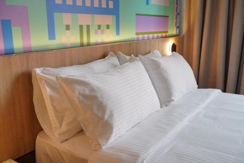a white bed with white pillows in a bedroom at The Graph Hotel in Kuala Lumpur
