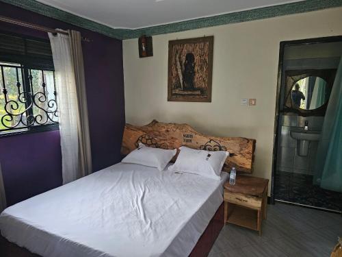 a bedroom with a white bed and a window at Nguru Farm Cottages in Wakiso