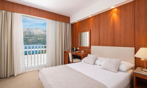 a bedroom with a bed and a large window at Marko Polo Maradiso Hotel by Aminess in Korčula
