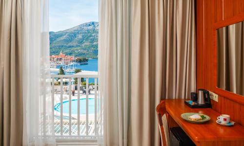 a room with a table and a window with a view at Marko Polo Maradiso Hotel by Aminess in Korčula
