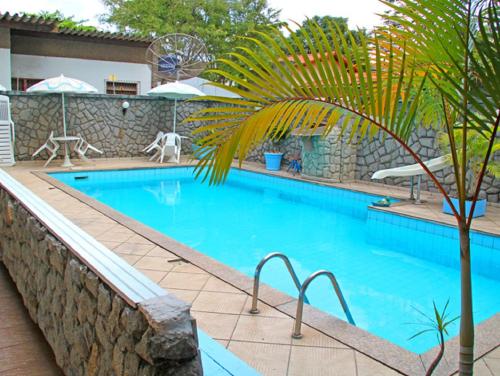 a large swimming pool with a palm tree next to it at Pousada Praia da Costa in Vila Velha