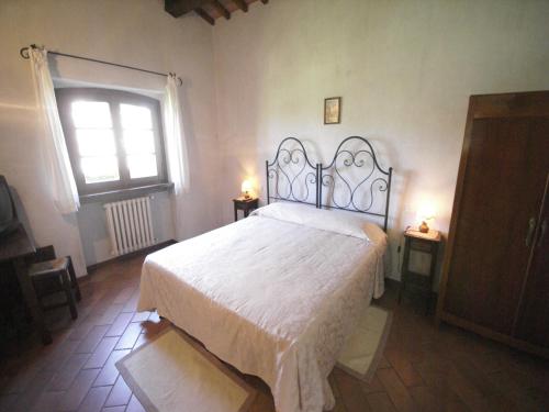 a bedroom with a bed with a white bedspread and a window at Nice apartment with pool and beautiful garden in Montone