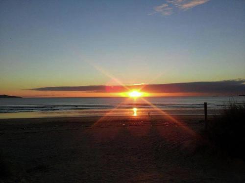 a sunset on the beach with the sun setting at Apartment with Sea Views in Sanxenxo