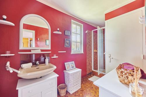 un bagno rosso con lavandino e specchio di Au Cèdre Bleu - Longère avec Grand Jardin a Livarot