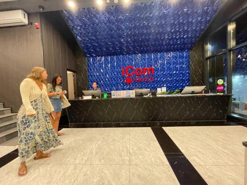 two women standing in front of a reception counter in a store at iCom Blue Seaview in Maafushi