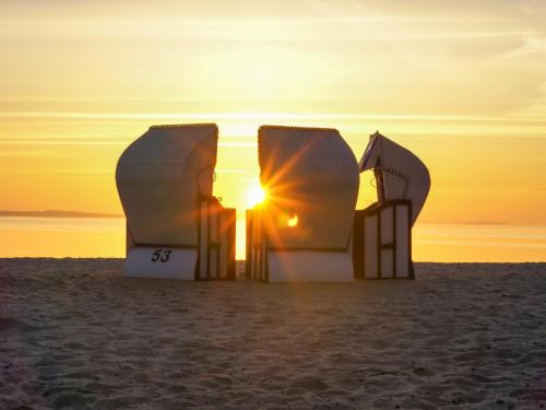 a pair of beach huts on the beach at sunset at Ground-floor apartment with terrace and large garden with lounge area and grill in Mönkebude