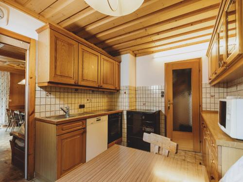 a kitchen with wooden cabinets and black appliances at holiday home, Fusch an der Glocknerstraße in Fusch an der Glocknerstraße