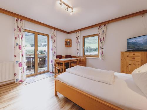 a bedroom with a bed and a table and windows at holiday home, Fusch an der Glocknerstraße in Fusch an der Glocknerstraße