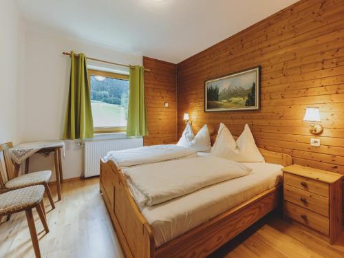 a bedroom with a bed and a chair and a window at holiday home, Fusch an der Glocknerstraße in Fusch an der Glocknerstraße