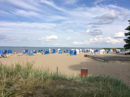 a group of people sitting on the beach at Ground-floor apartment with terrace and large garden with lounge area and grill in Mönkebude