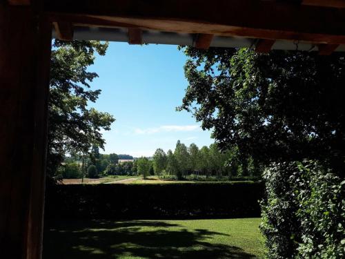 a view of a garden from a wooden archway at Holiday home with pool in Verteillac in Verteillac
