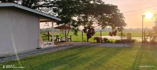 una casa con una mesa y una sombrilla en un campo en villa tempoyak homestay, en Pantai Cenang