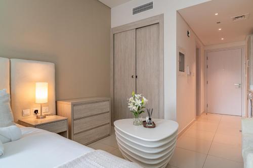 迪拜Seven Palm Jumeirah Studio - Private Beach Access的一间卧室，里面有一张床和一张摆着鲜花的桌子