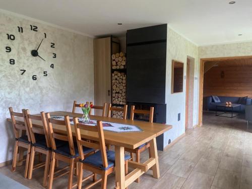 a dining room with a table and a clock on the wall at Chatka Puchatka in Tenczyn