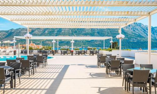 a patio with tables and chairs and a pool at Marko Polo Maradiso Hotel by Aminess in Korčula