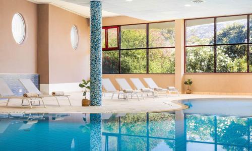 a pool in a hotel with chairs and a swimming pool at Marko Polo Maradiso Hotel by Aminess in Korčula