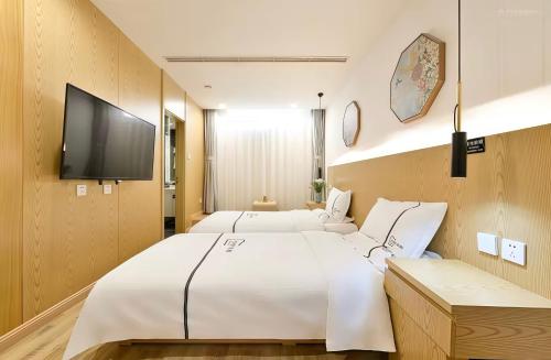 a bedroom with two beds and a flat screen tv at Xingshe Alley Courtyard Hotel Beijing Wangfujing Forbidden City Branch - Breakfast included & English speaking reception & Free WiFi and Laundry room & Hutong Culture & Cat-keeping & Flower-growing Terrace & One day tour service & Free coffee in Beijing