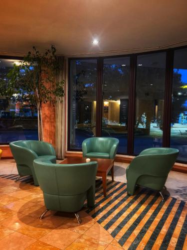 a lobby with green chairs and a table and windows at Euro Hotel in Nuoro