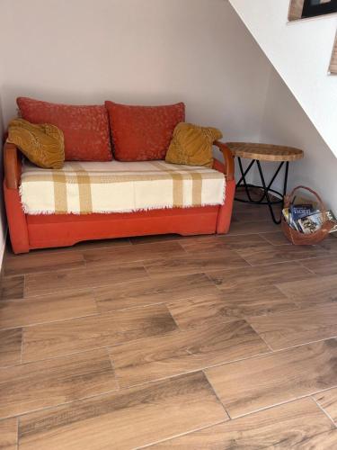 an orange couch in a room with a wooden floor at Sky Peak in Stare Bystre