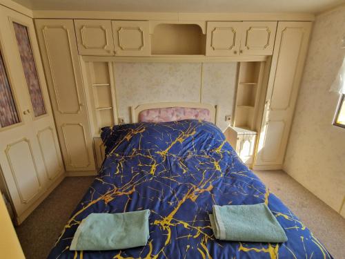 a bedroom with a bed with a blue comforter at Przyczepa holenderska ROCO in Rewa