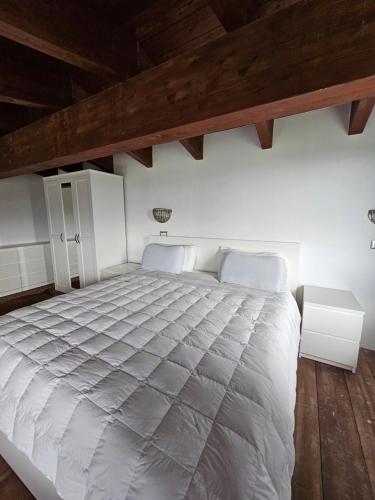 a large white bed in a room with wooden ceilings at La Magia Lucana in Colobraro