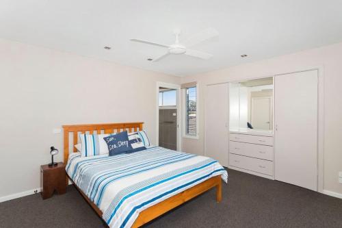 a white bedroom with a bed and a dresser at Dolphin Views in Burrill Lake