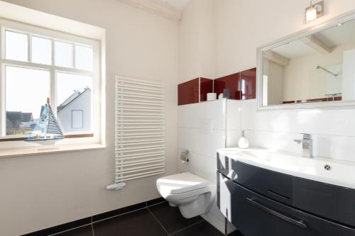 a bathroom with a toilet and a sink and a window at Haus Ostseestrand in Lancken