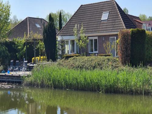 a house next to a river with grass at Family Home in Zeewolde by Forest Trails in Zeewolde