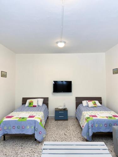 a bedroom with two beds and a flat screen tv at Casa Riviera in Zahlé