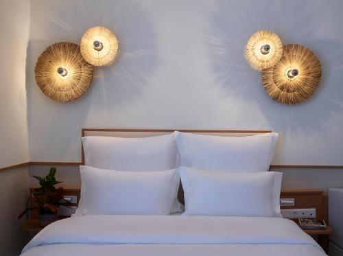 a bedroom with a bed with white sheets and two mirrors at Brown Beach Chalkida Resort, a member of Brown Hotels in Chalkida
