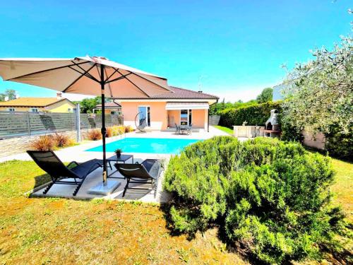 a patio with two chairs and an umbrella next to a pool at Family house Hana in Kanfanar