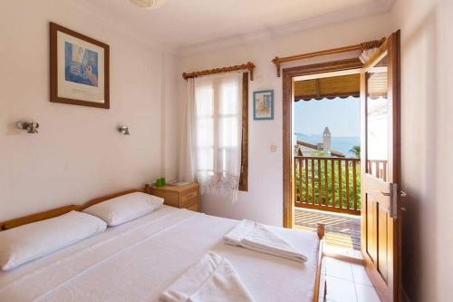 a white bedroom with a bed and a balcony at The White House Kalkan in Kalkan