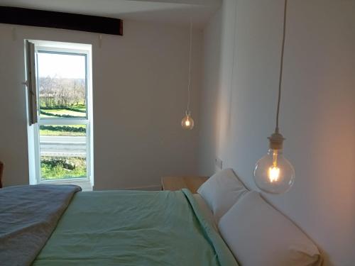 a bedroom with a bed with a window and two lights at Duplex en Ribeira Sacra in Sistín